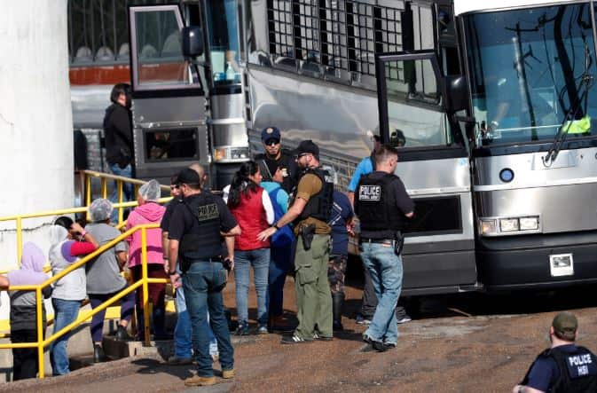 Handcuffed workers are escorted by ICE agents during the raids. 