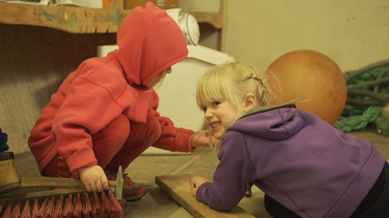 Girls play with a hammer and nails. 