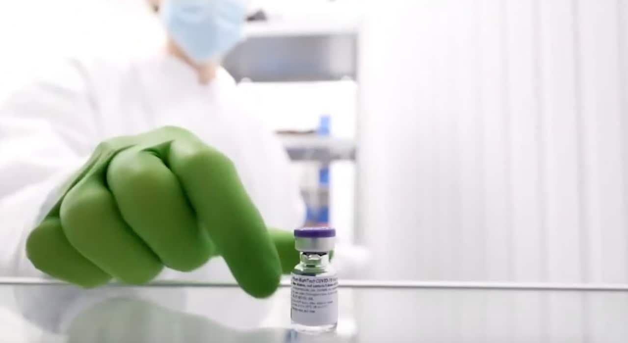 A health worker reaches for a vile of mRNA vaccine