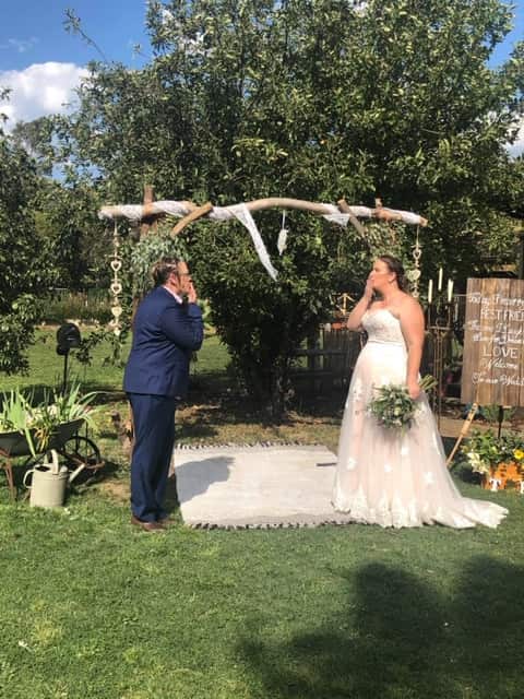 Kat and Terri blowing each other kisses underneath their homemade arbor. 