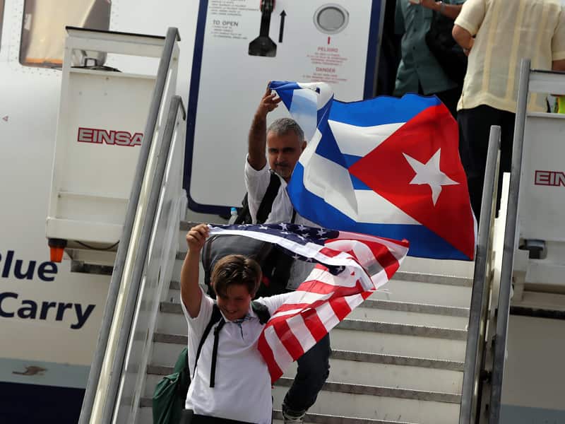 People waving Cuban and US national flags disembark from a plane