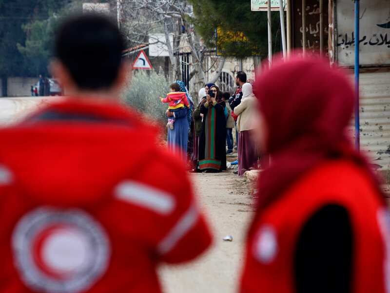 Members of the Syrian Red Cross stand near aid vehicles in Madaya