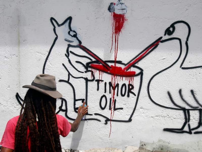 An Timor-Leste activist paints Australian Embassy's wall in Dili