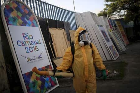 A person in a yellow hazmat suit, standing in front of a Rio Carnaval sign.