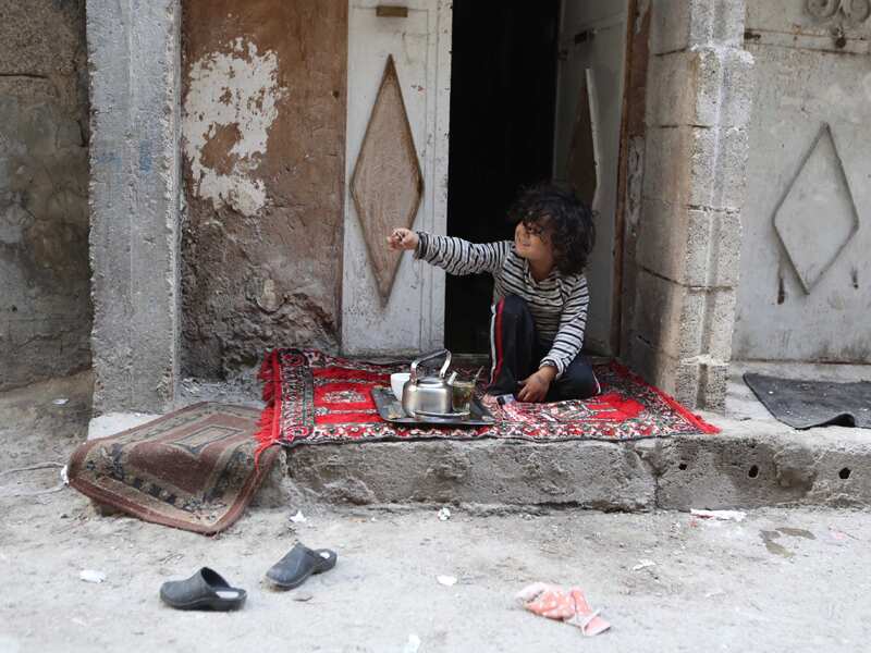 A Syrian boy sits in front of his home after a ceasefire