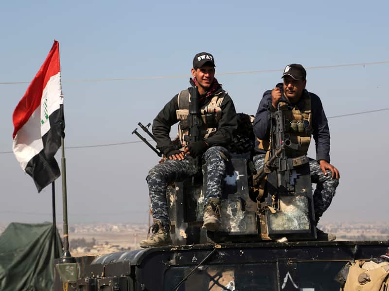 Two policemen sit atop of their vehicle west of Mosul