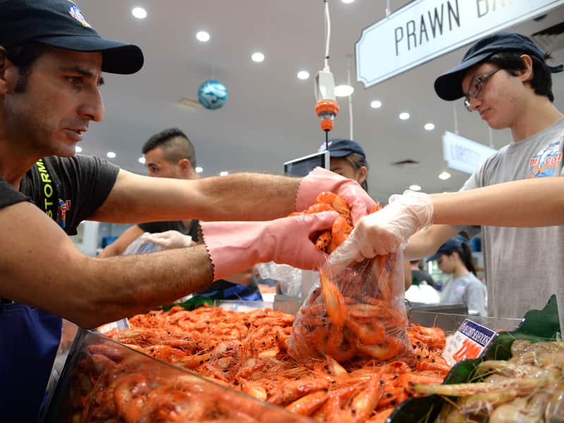A fish market worker packs prawns for customers
