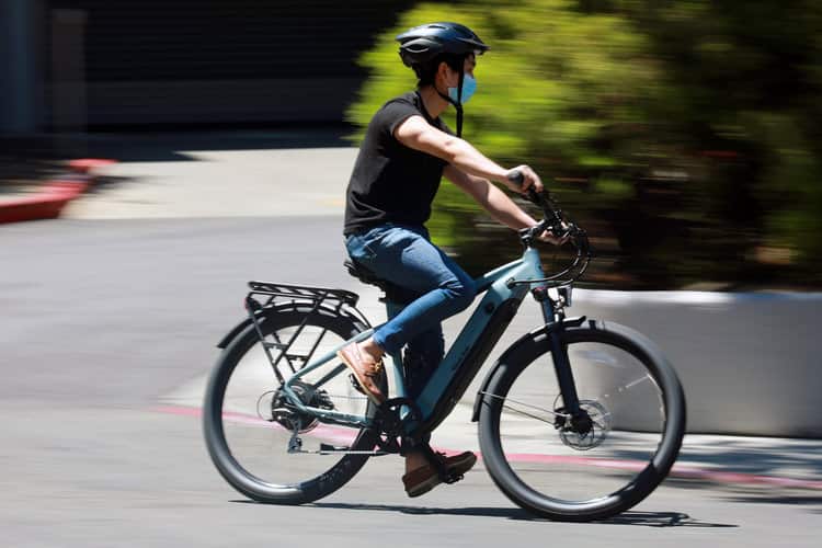 an ebike is being ridden by a man wearing a face mask