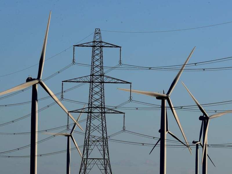 A view of a wind farm amongst electricity pylon.