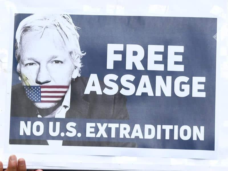 Supporters of Julian Assange holding up placards at a rally.