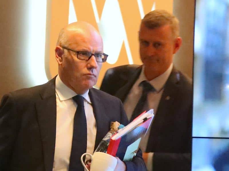 Executive editor of ABC News John Lyons is followed by an Australian Federal Police officer as they leave the office after the raid.