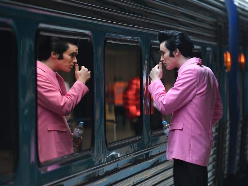 Elvis impersonator Brody Finlay looks at his reflection in a train