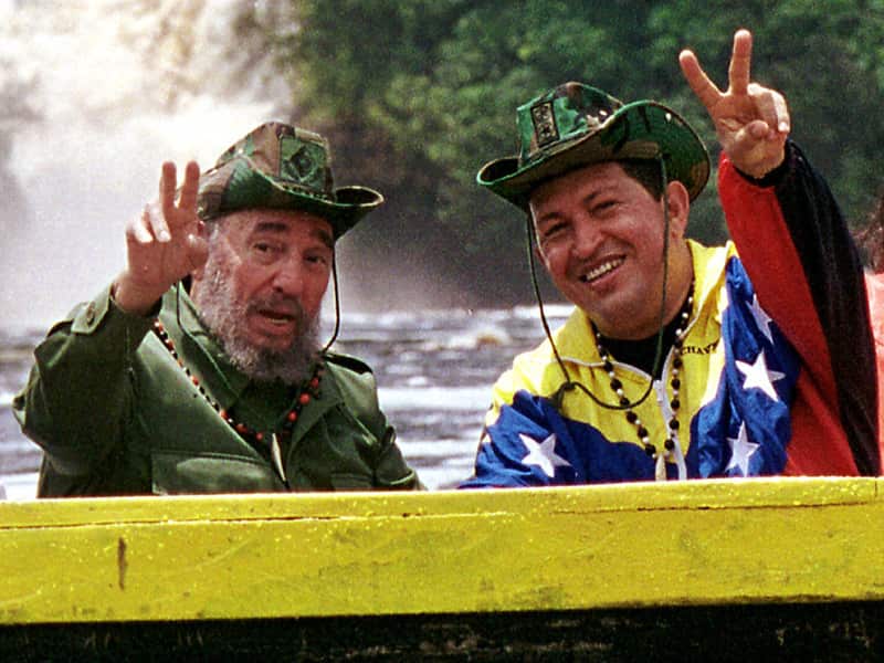 Cuba's President Fidel Castro and Venezuela's President Hugo Chavez wave to a crowd while touring Canaima National Park in eastern Venezuela in a canoe in 2001. Fidel Castro and Chavez stayed close friends and allies. (AAP)