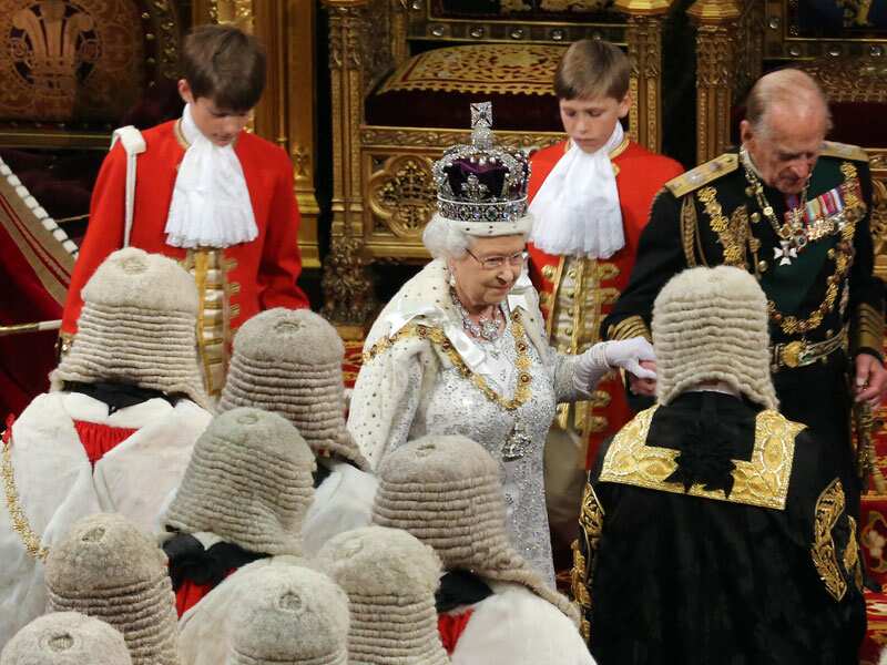 Queen Elizabeth II, wearing a crown, at an indoor ceremony