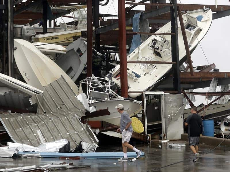 People walk past a damaged boat storage facility in Rockport, Texas
