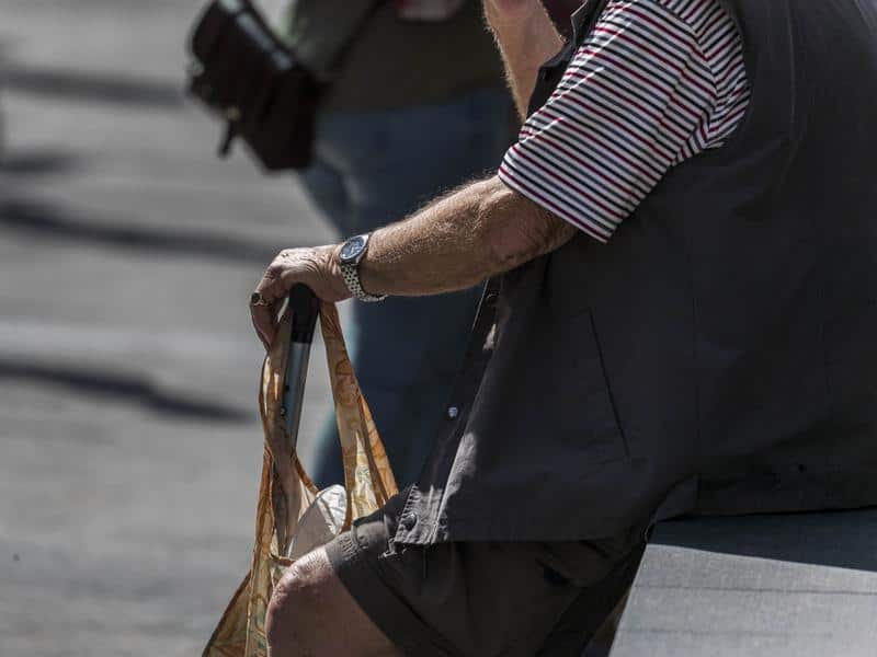 An elderly man sits on a bench