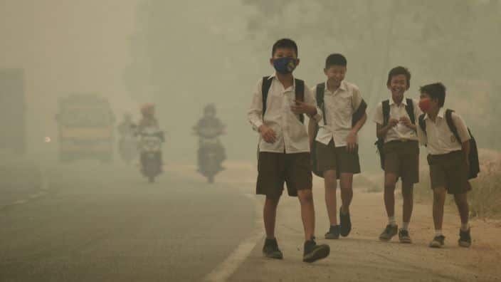 Children walking through heavy smog.