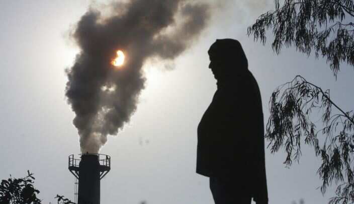 Silouhette of a person in front of a coal plant.