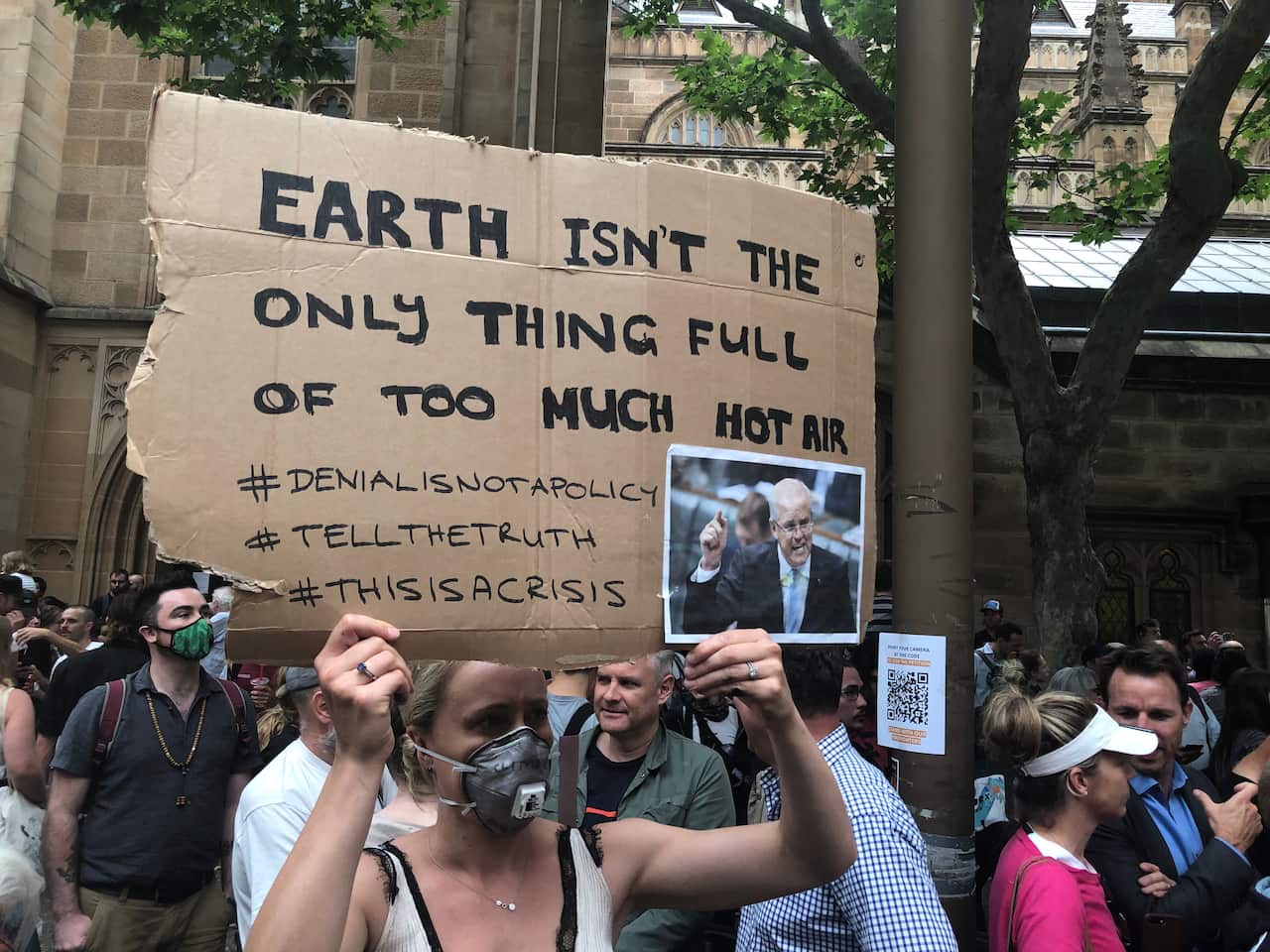A protester holds up a picture of Scott Morrison with the caption "earth isn't the only thing full of too much hot air"