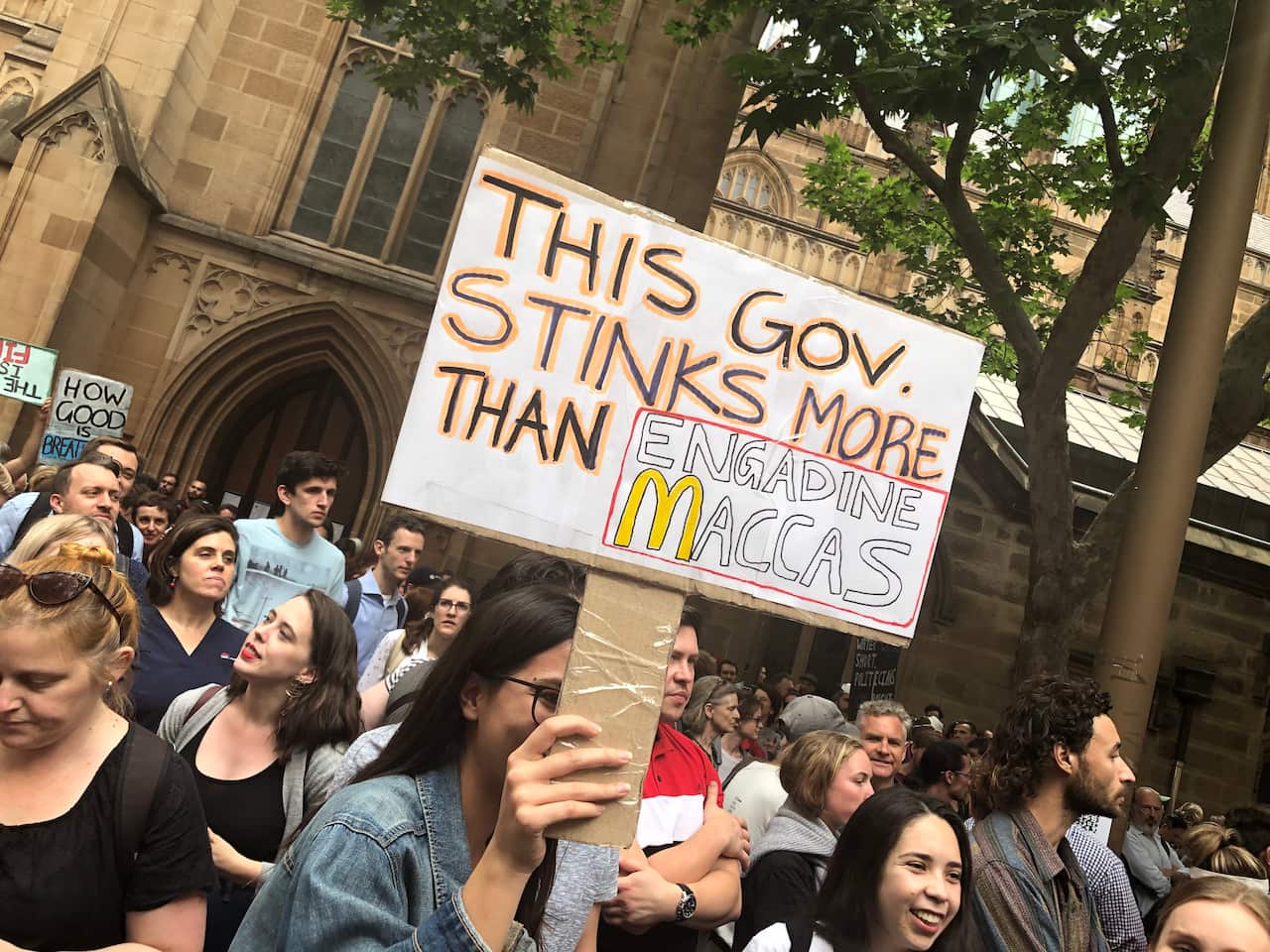 A protest signs reads "This gov stinks more than Engadine Maccas"