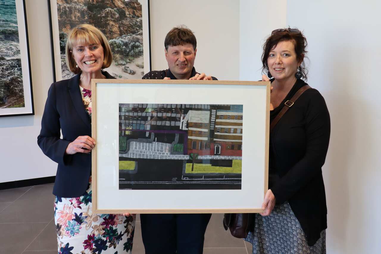 NDIA Acting CEO Vicki Rundle (left), artist  Christian Den Besten and his mentor Sharon Bromley from Arts Gusto with Christian’s artwork 'NDIS Carlton Hotel'.
