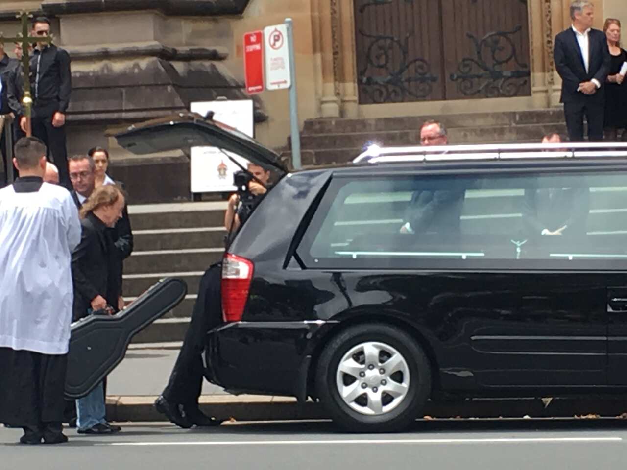 Angus Young places his brother's Gretsch guitar alongside his brother's coffin.