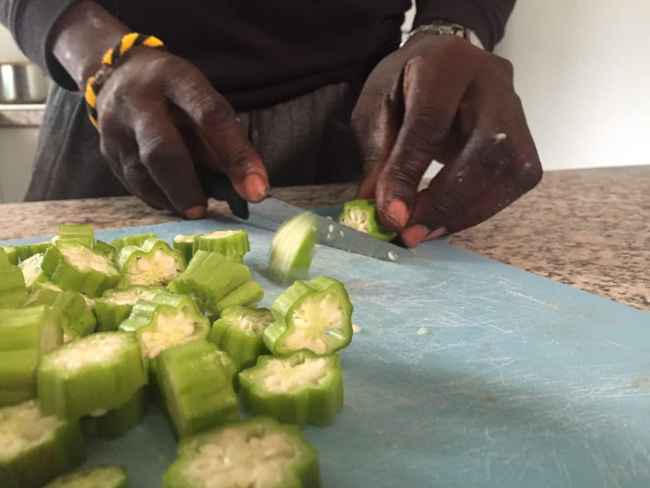 South Sudanese Dinka man Mana Athian chops okra grown in his back yard in Brisbane.