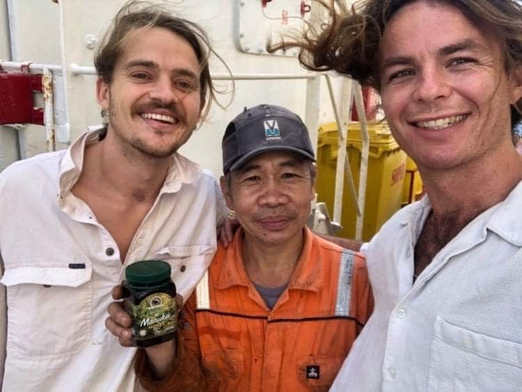 Will Mainprize (far right) and friend Harry Morrison presenting a crew member with a gift of Manuka honey, July 2020.