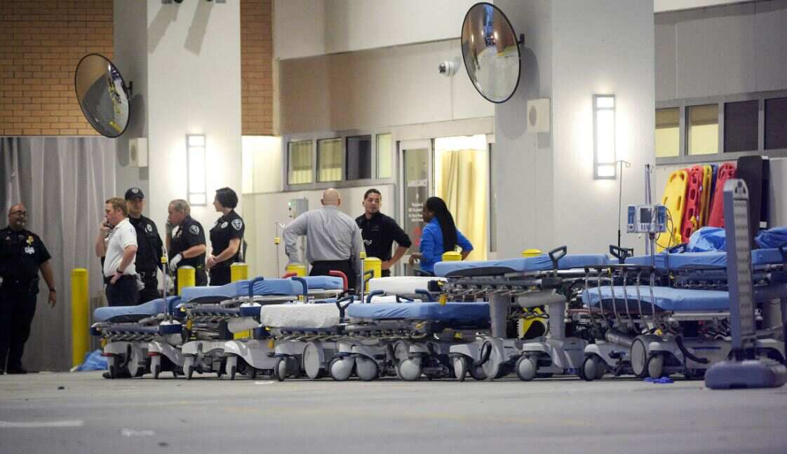 Uniformed staff wait at the door in front of a row of empty stretchers.