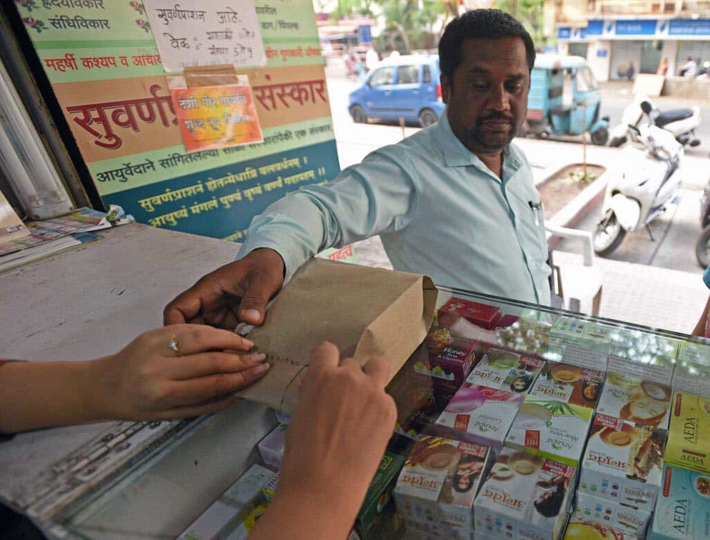 A shopkeeper selling medicines in paper bags in Pune, India.