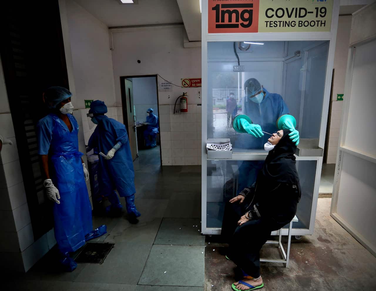 A health worker takes a nasal swab of a woman for COVID-19 test at a hospital in New Delhi, India.