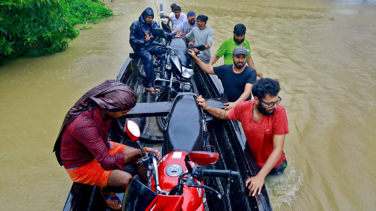 People salvage motorcycles in a country boat in a flooded area at Kainakary in Alappuzha district, Kerala state.