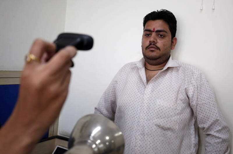 An Indian man poses for a photograph as part of the  Aadhaar card enrollment process.