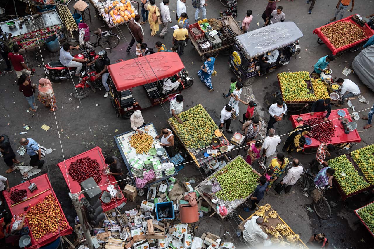 Electric rickshaws ride into a narrow lane surrounded by pedestrians and hand carts in New Delhi, July 1, 2019. (Saumya Khandelwal/The New York Times)