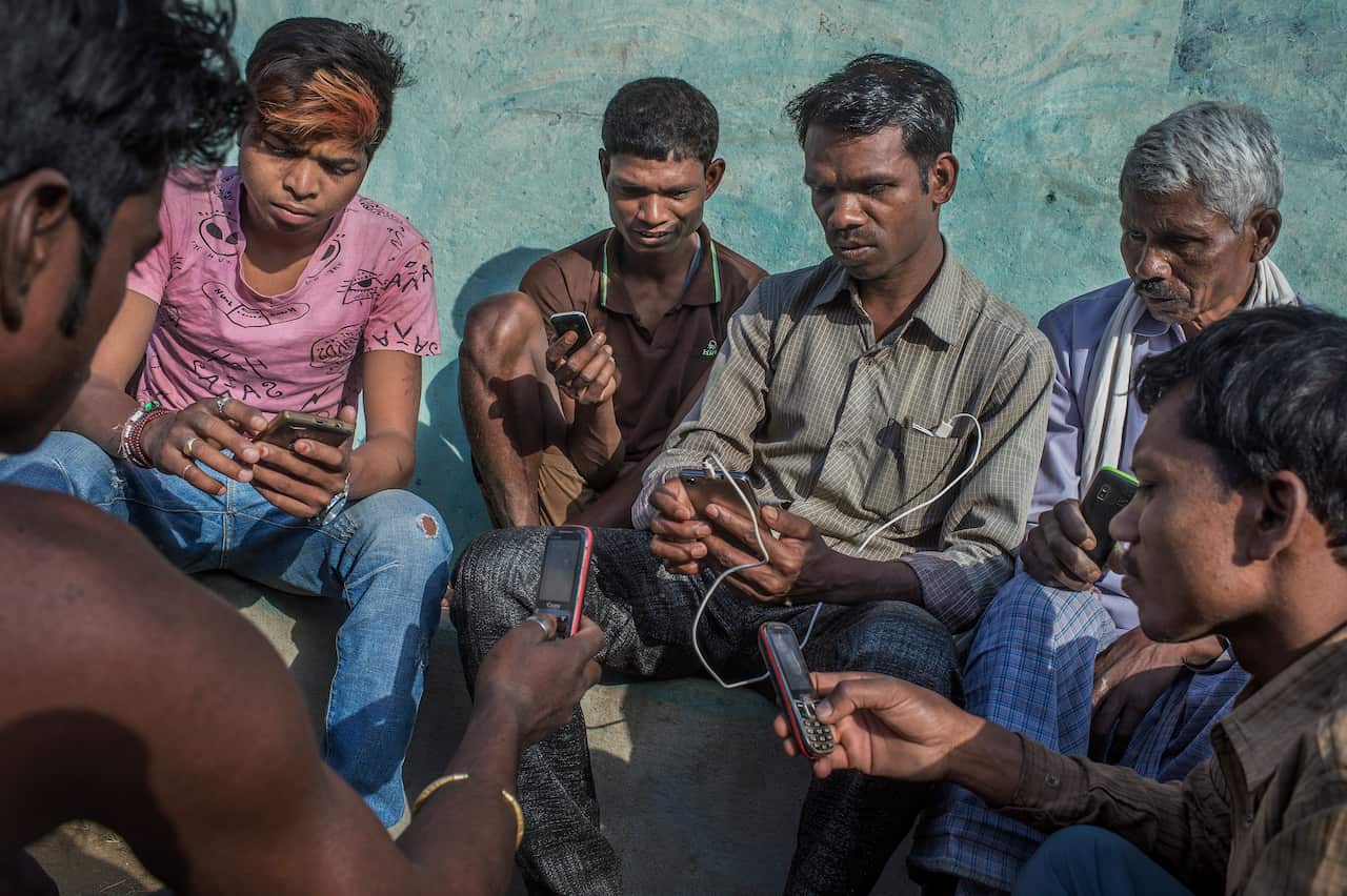 Babulal Singh Neti, center, teaches villagers how to use mobile phones in Taradand, India.