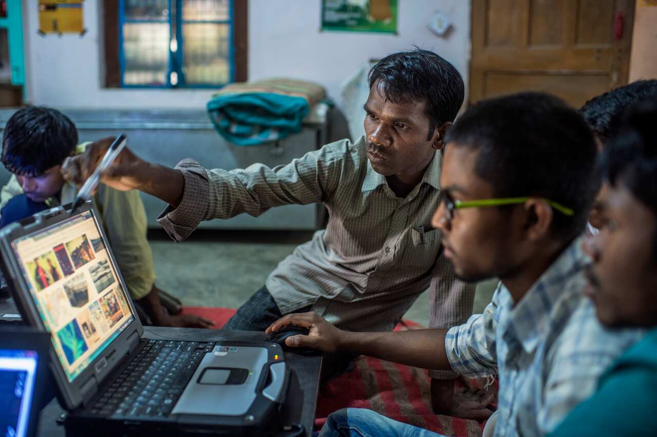 Babulal Singh Neti teaching trainees how to use Google on a laptop.