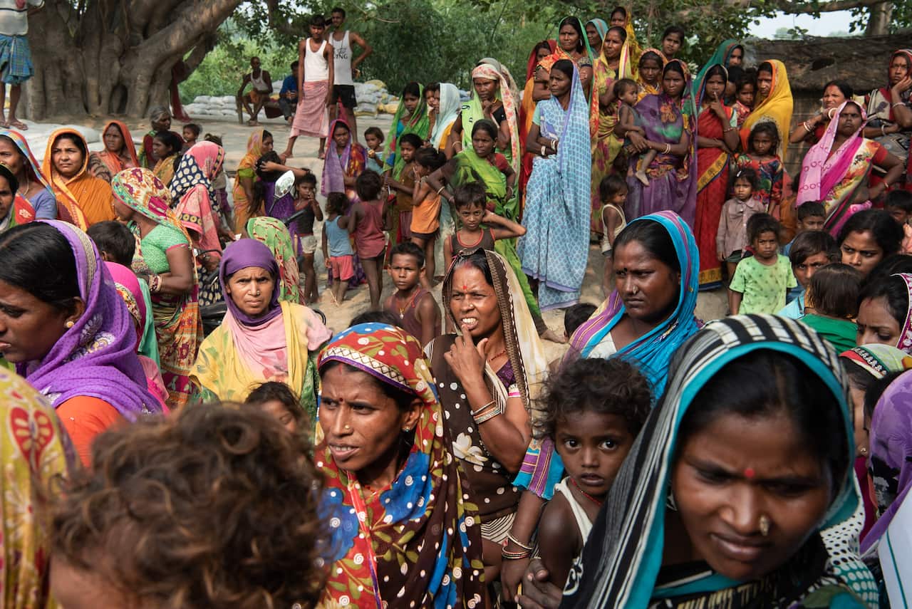 People gather to receive glucose biscuits being given out by aid groups. Officials say a child suffering “the lychee disease” should be givem sugar and salt.