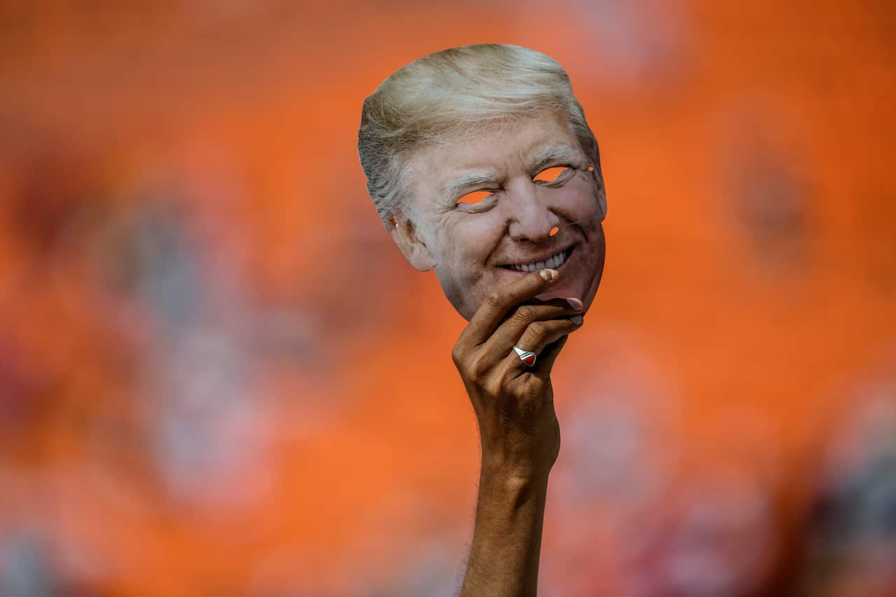 A person displays a mask depicting President Donald Trump, during an event with Trump and Indian Prime Minister Narendra Modi at Motera Stadium in Ahmedabad.