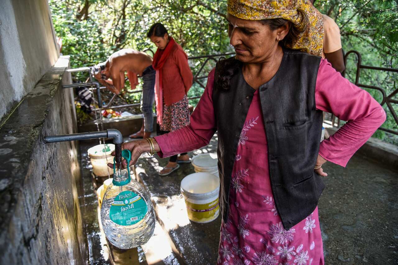 Residents make use of a natural water source in Shimla, India.