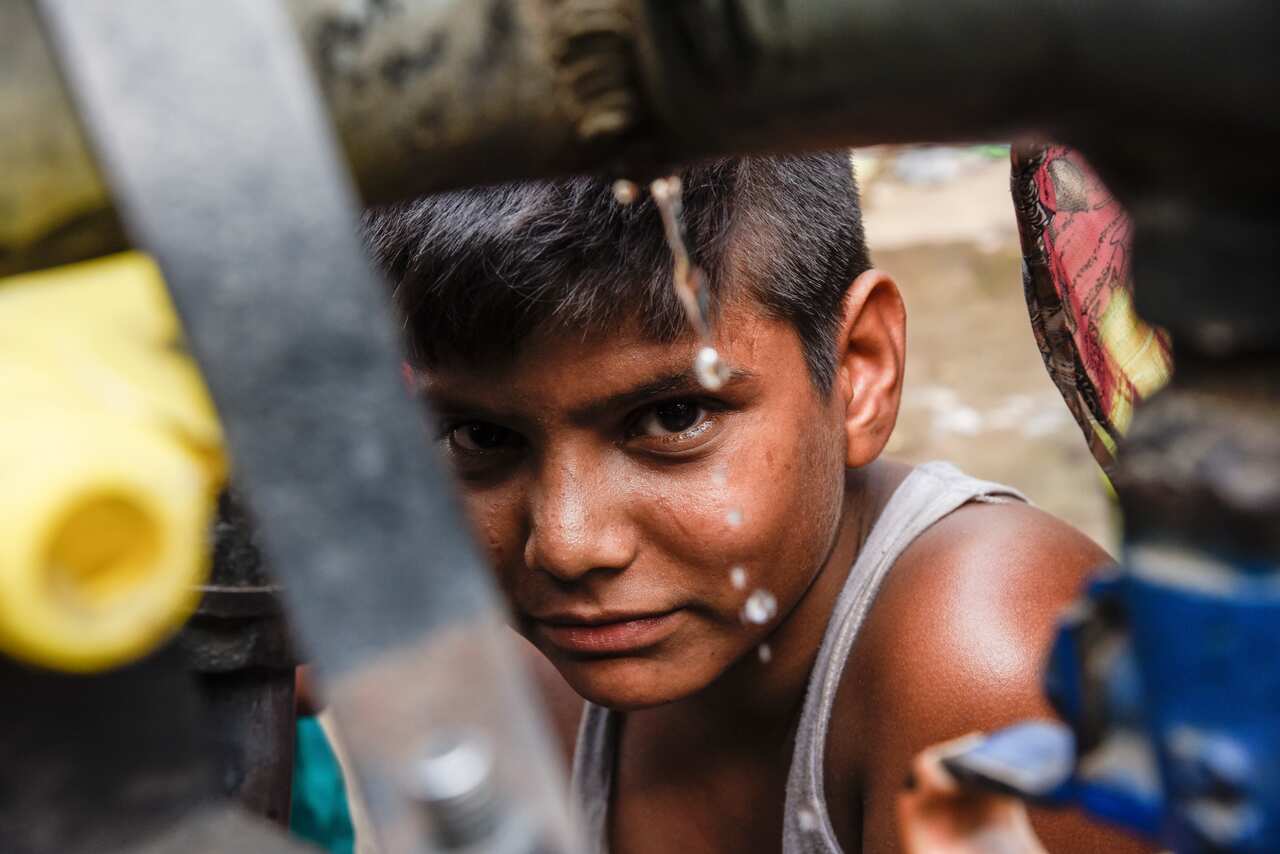A child looks on as a water tanker is used to fill containers in the Wazirpur neighborhood of New Delhi, India. 