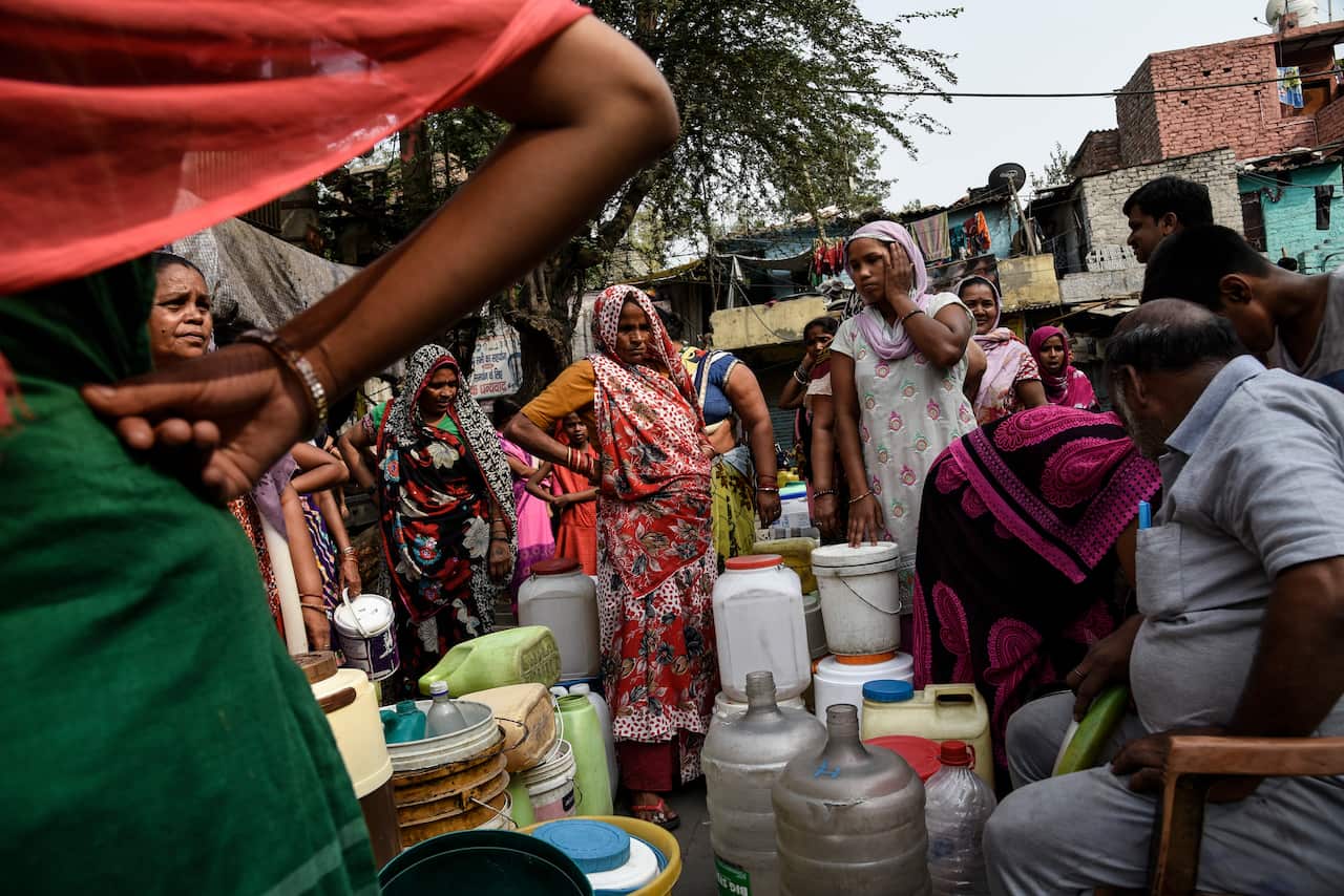 People queue up for a water tanker in the Wazirpur neighborhood of New Delhi, India.