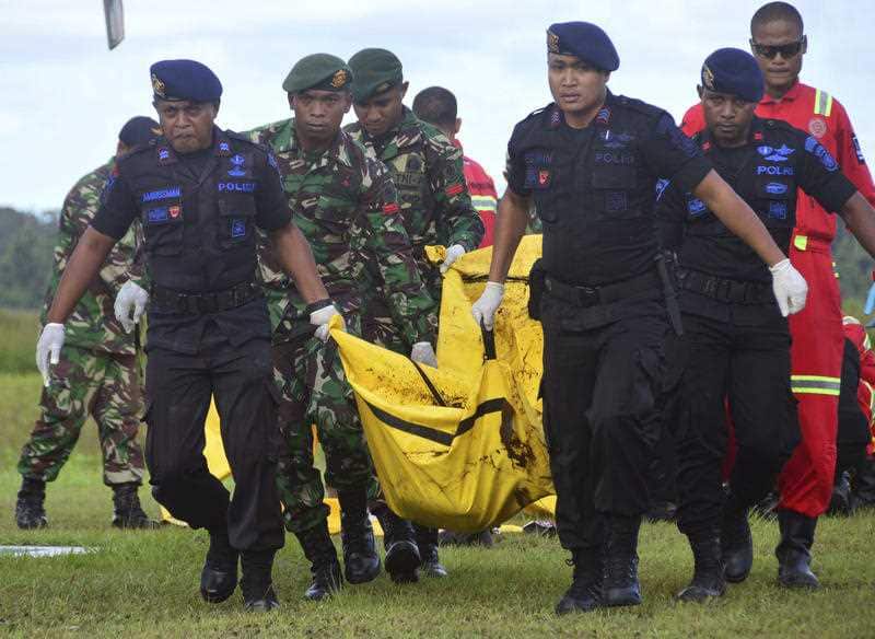 Indonesian soldiers and police officers carry a body bag containing the body of a victim of separatist attack in Nduga.