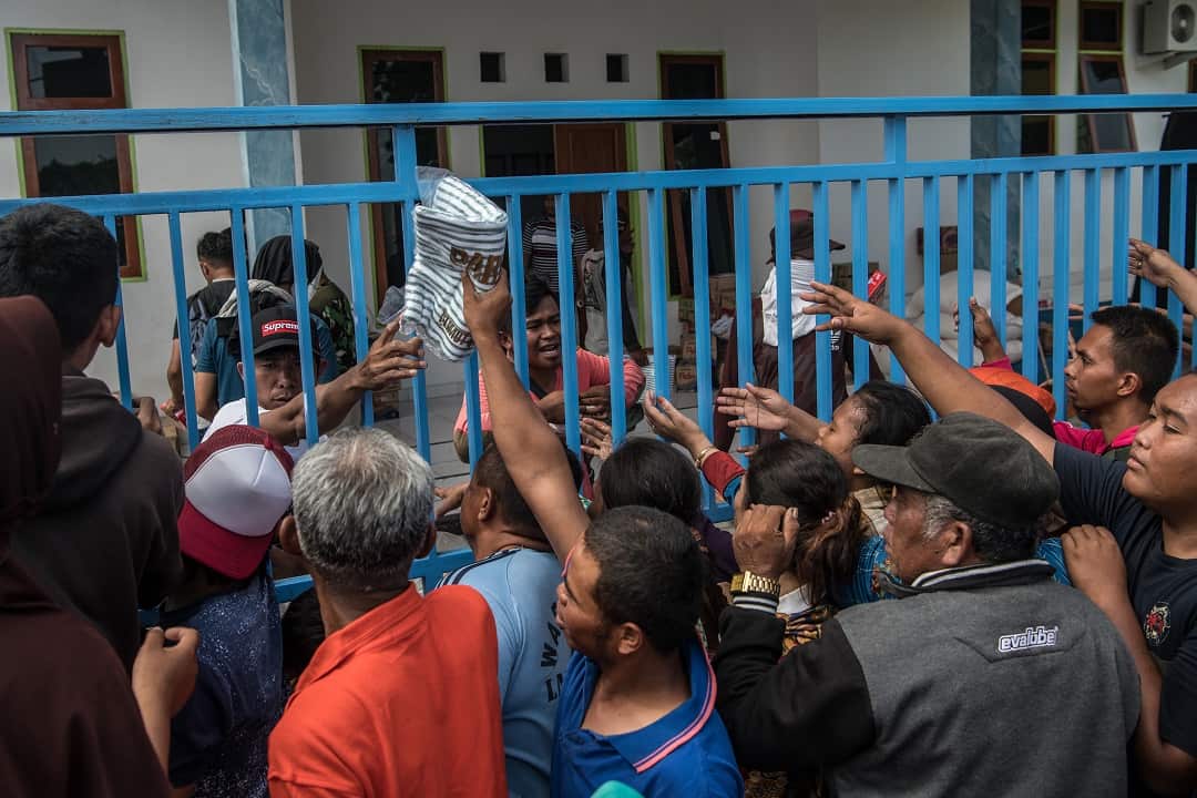 Children and adults grab food being distributed by the military.