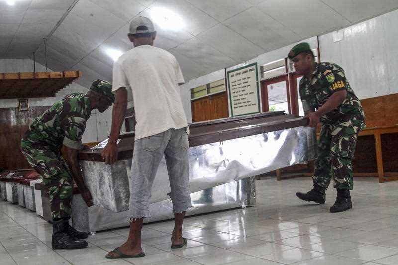 Indonesian military personnels and workers prepare coffins for the slain construction workers.
