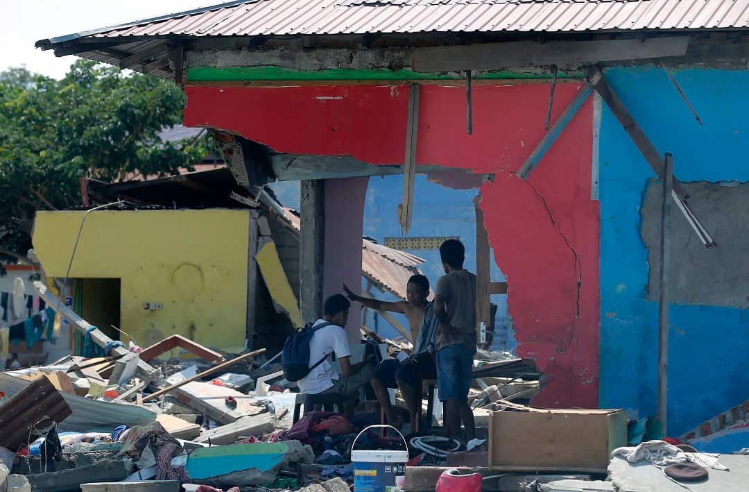 Villagers chat amongst the damage caused by the earthquake and tsunami in Palu.