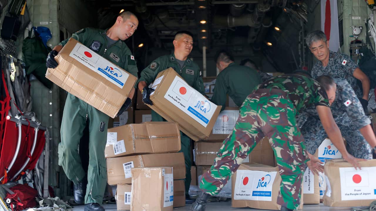 Indonesian and Japan military personnel unload relief aid from a Japan Air Force cargo plane at the Mutiara Sis Al-Jufri airport in Palu.