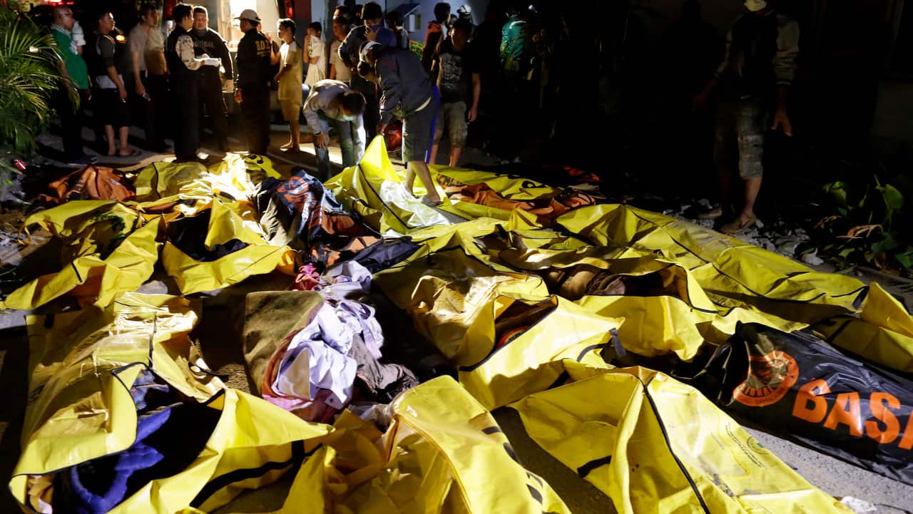 Indonesian men check the body of earthquake and tsunami victims as they look for their relatives at a police hospital in Palu, central Sulawesi.