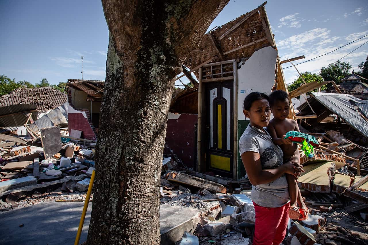 A mother and son stand near the ruins of their home following the quake.