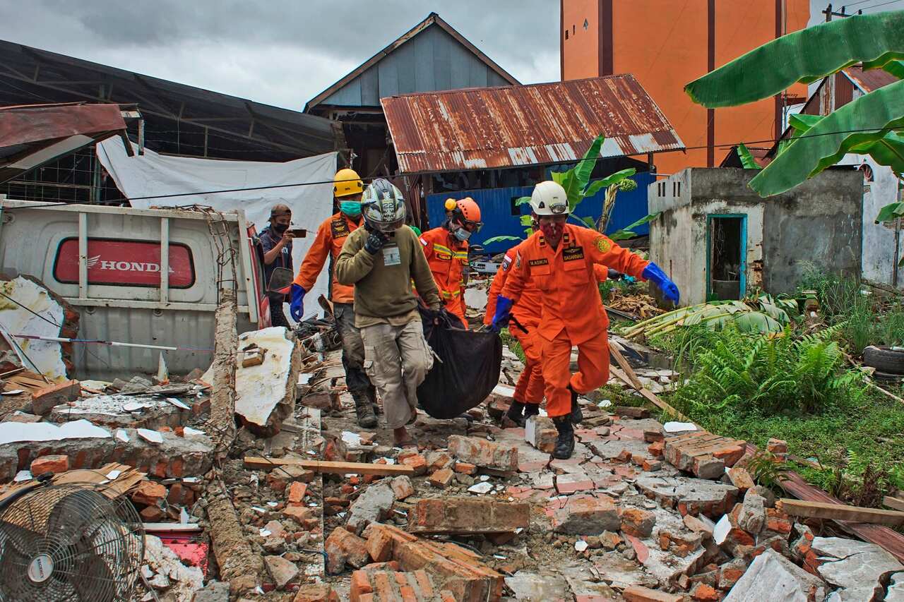 Recuers carry a body bag containing a victim of an earthquake in Mamuju, West Sulawesi, Indonesia.