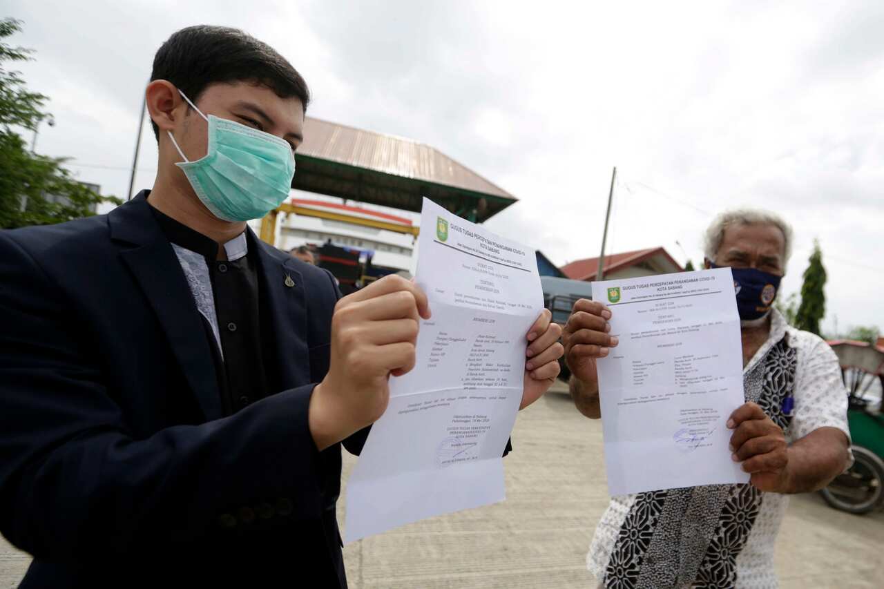 People show their travel permit letters, issued by Aceh Government, at Ulee Lhuee port in Banda Aceh.